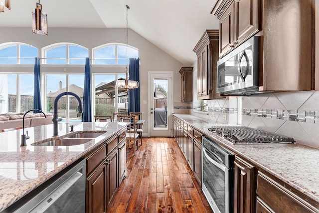 kitchen with hanging light fixtures, stainless steel appliances, dark brown cabinets, a chandelier, and a sink