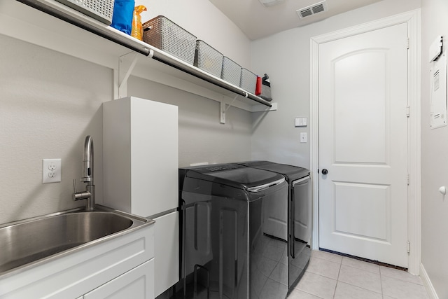 laundry room featuring washing machine and clothes dryer, light tile patterned floors, visible vents, a sink, and laundry area