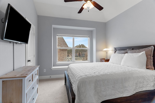 bedroom featuring light carpet, baseboards, vaulted ceiling, and a ceiling fan