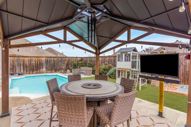 view of patio / terrace with a fenced in pool, a playground, a fenced backyard, and a storage unit