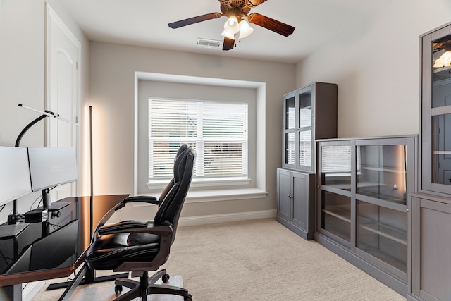 office space with light colored carpet, visible vents, ceiling fan, and baseboards