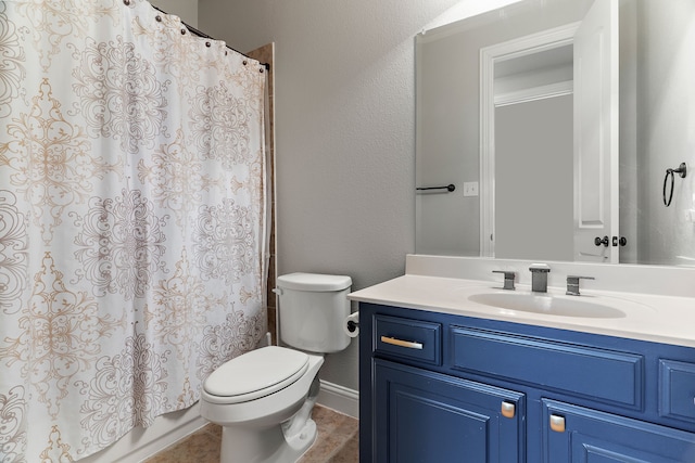 bathroom with toilet, a textured wall, tile patterned floors, and vanity