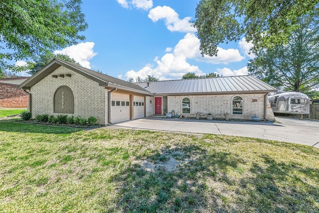 single story home with metal roof, a garage, brick siding, driveway, and a front yard