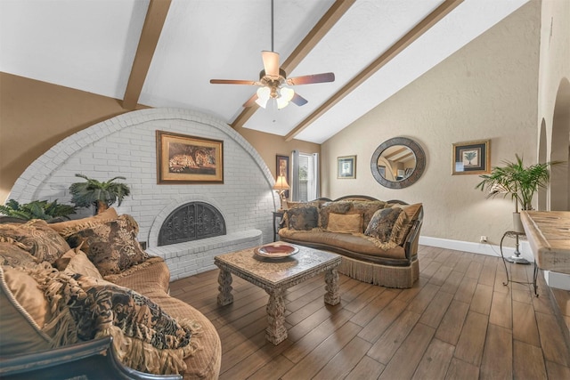 living room featuring lofted ceiling with beams, a brick fireplace, baseboards, and wood finished floors