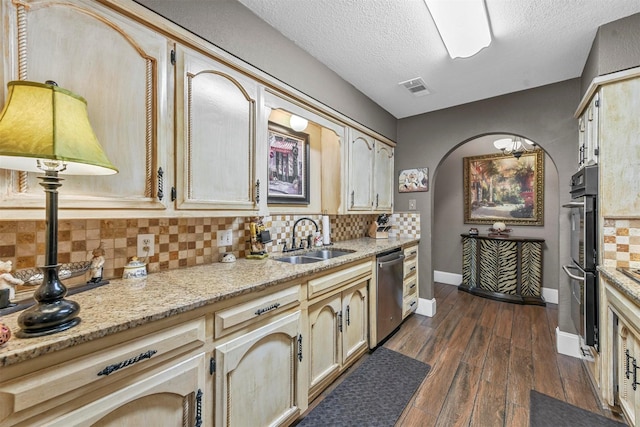 kitchen with a sink, visible vents, appliances with stainless steel finishes, backsplash, and dark wood finished floors