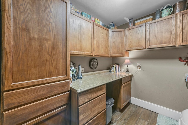 kitchen featuring baseboards, light countertops, and wood finished floors