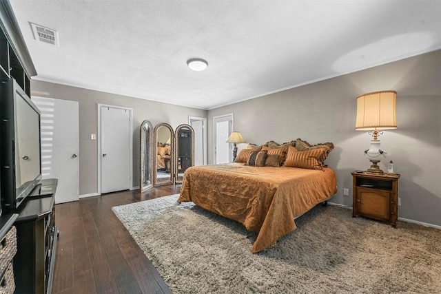 bedroom featuring crown molding, dark wood finished floors, visible vents, a textured ceiling, and baseboards