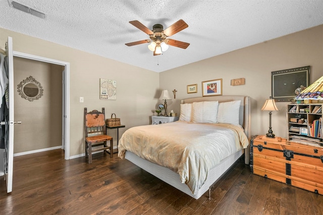 bedroom featuring baseboards, visible vents, a ceiling fan, dark wood-type flooring, and a textured ceiling