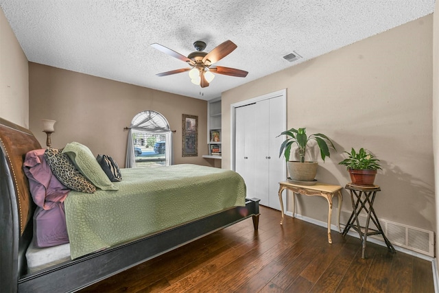 bedroom with dark wood-style floors, a closet, visible vents, and a textured ceiling