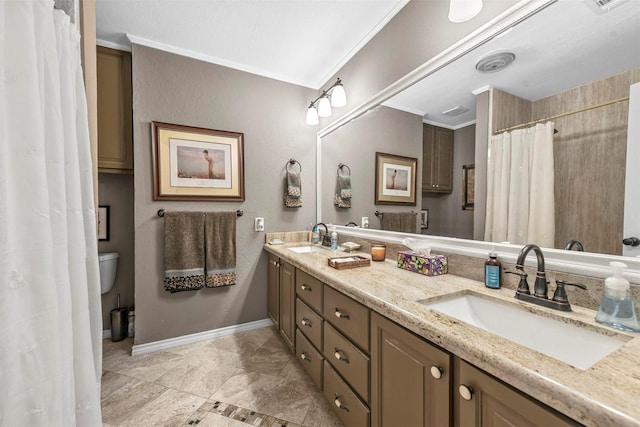 bathroom featuring ornamental molding, a sink, baseboards, and double vanity