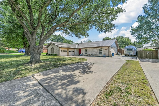 ranch-style house with brick siding, an attached garage, a front yard, metal roof, and driveway