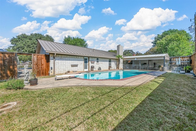 view of swimming pool with a diving board, a lawn, and fence