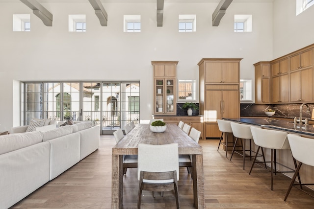 dining area featuring light wood-type flooring and beam ceiling