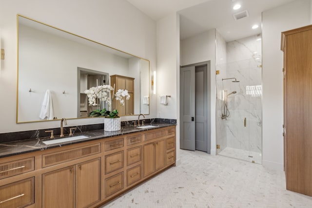 bathroom featuring visible vents, a sink, a marble finish shower, and double vanity