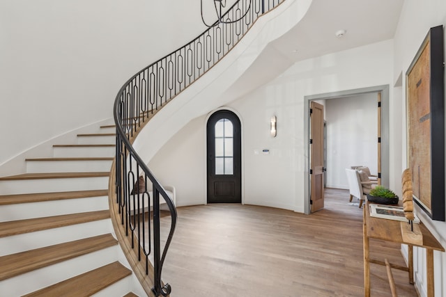 entrance foyer featuring a towering ceiling, light wood-style flooring, and stairs