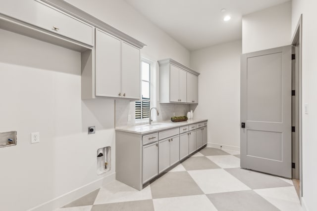 laundry area with light floors, cabinet space, hookup for an electric dryer, a sink, and baseboards