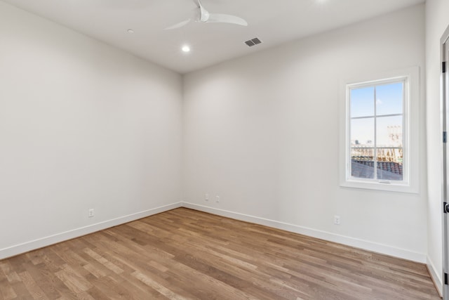 empty room featuring ceiling fan, light wood finished floors, visible vents, and baseboards