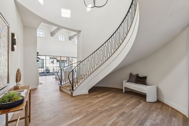 stairs with a high ceiling, wood finished floors, and baseboards