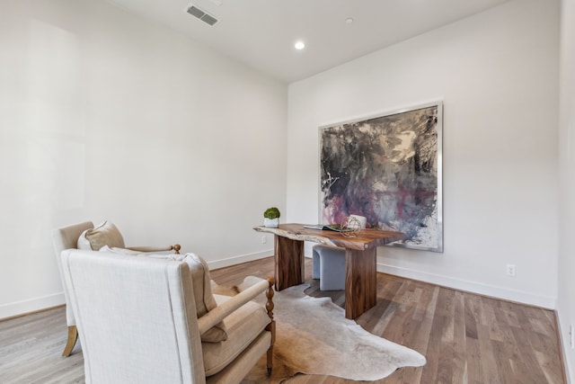 living area featuring light wood-style flooring, visible vents, and baseboards