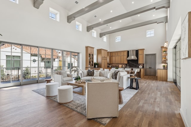 living area featuring light wood-style floors, a wealth of natural light, and beamed ceiling