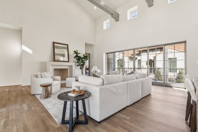 living room featuring a wealth of natural light, beamed ceiling, a high ceiling, and wood finished floors