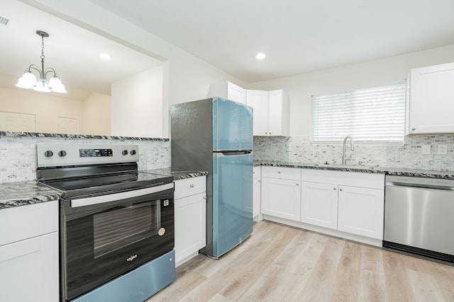 kitchen featuring light wood finished floors, appliances with stainless steel finishes, a sink, and white cabinetry