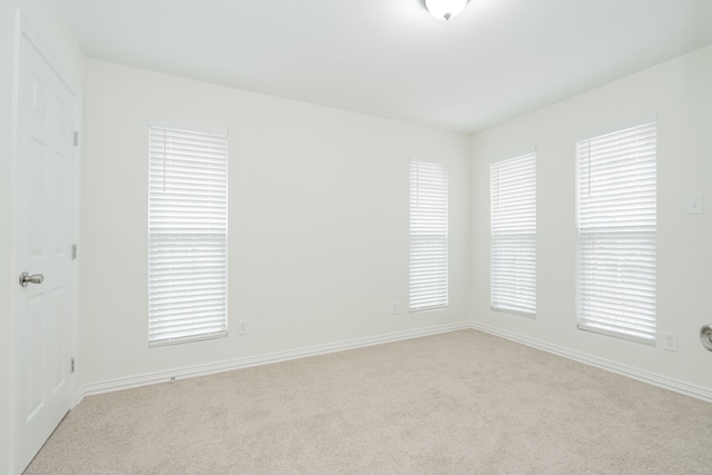 empty room featuring light carpet and baseboards