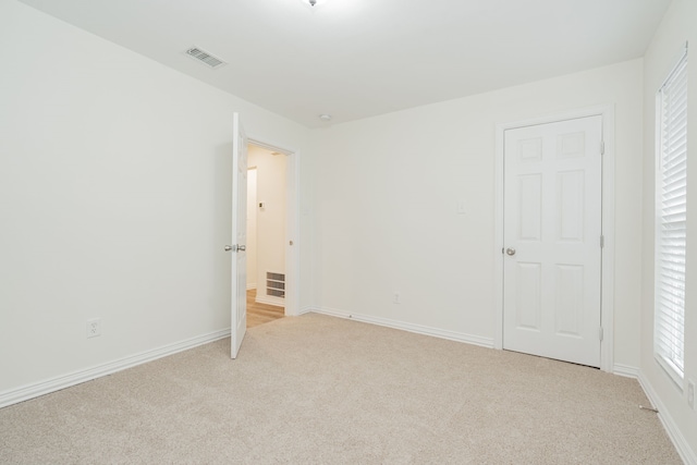 unfurnished bedroom with baseboards, visible vents, and light colored carpet