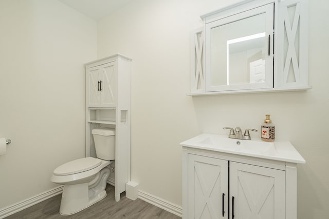 bathroom featuring vanity, wood finished floors, toilet, and baseboards