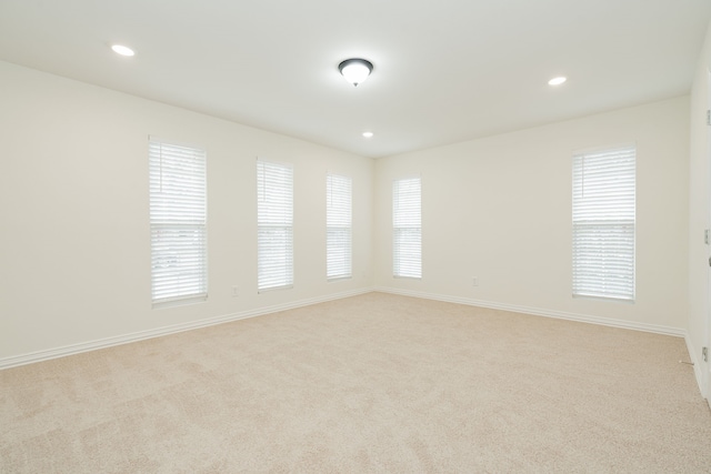 unfurnished room with baseboards, light colored carpet, a wealth of natural light, and recessed lighting