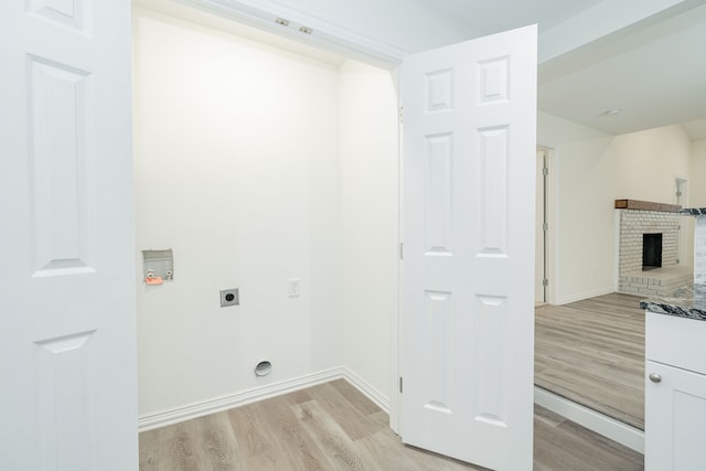 laundry room with light wood-style floors, a brick fireplace, laundry area, and electric dryer hookup