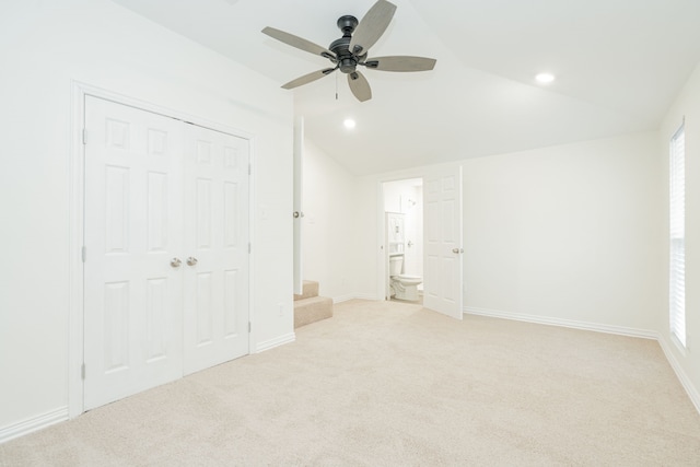 unfurnished bedroom with lofted ceiling, recessed lighting, light carpet, ensuite bath, and baseboards