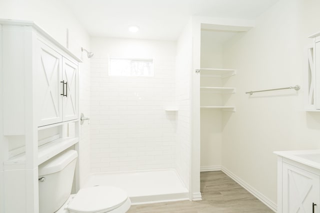 bathroom with a stall shower, baseboards, toilet, wood finished floors, and vanity