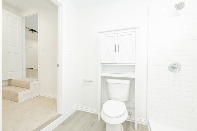 full bath featuring baseboards, tiled shower, toilet, and wood finished floors