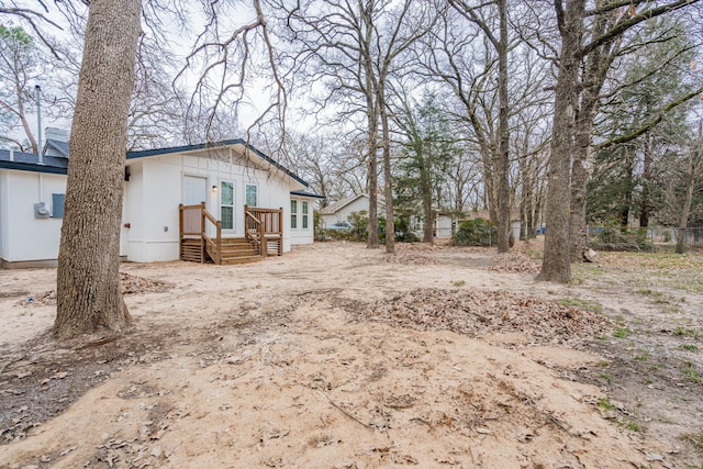 view of yard featuring entry steps, dirt driveway, and fence