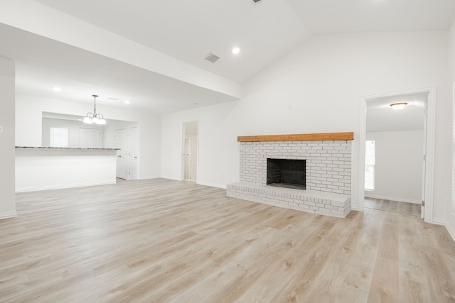1345 Tawakoni Dr, West Tawakoni, TX 75474 - unfurnished living room featuring light wood-style flooring, visible vents, an inviting chandelier, vaulted ceiling, and a brick fireplace