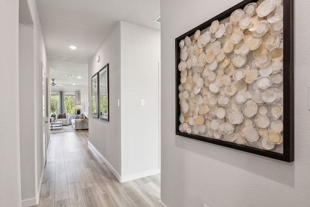 hallway featuring light wood-style floors, baseboards, and recessed lighting