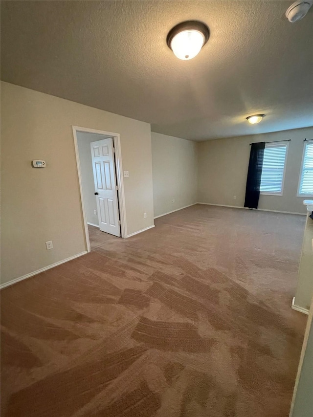 carpeted spare room featuring a textured ceiling and baseboards