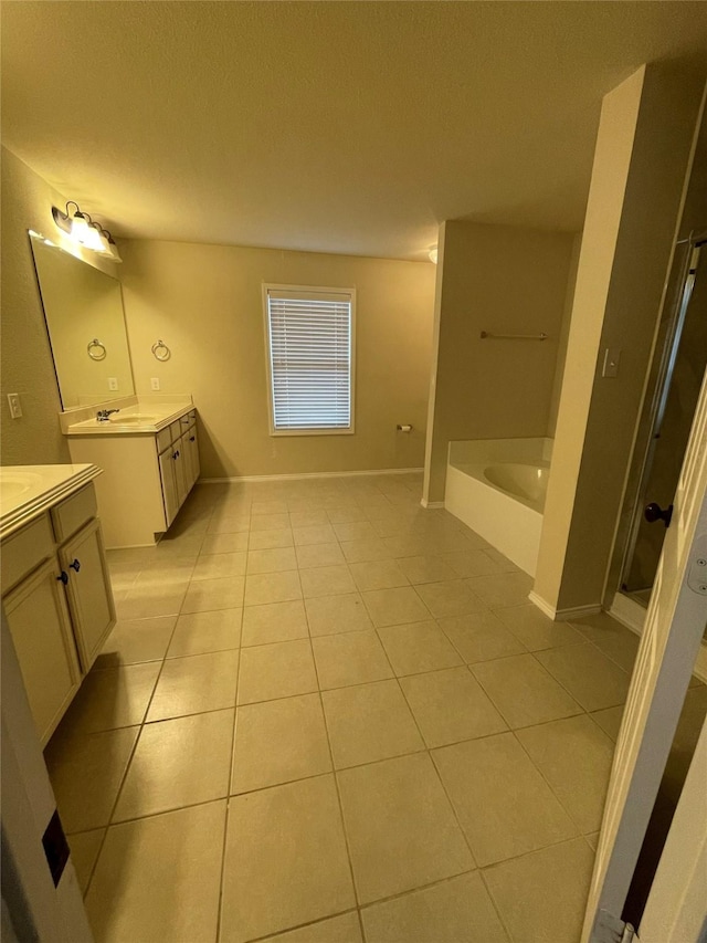 full bath with baseboards, a garden tub, tile patterned flooring, a textured ceiling, and two vanities