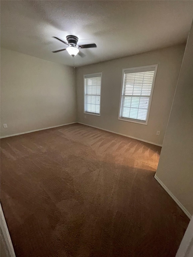 carpeted empty room featuring ceiling fan, a textured ceiling, and baseboards