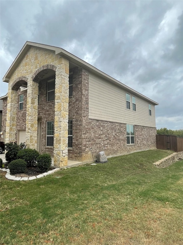 view of home's exterior with a yard, brick siding, and fence