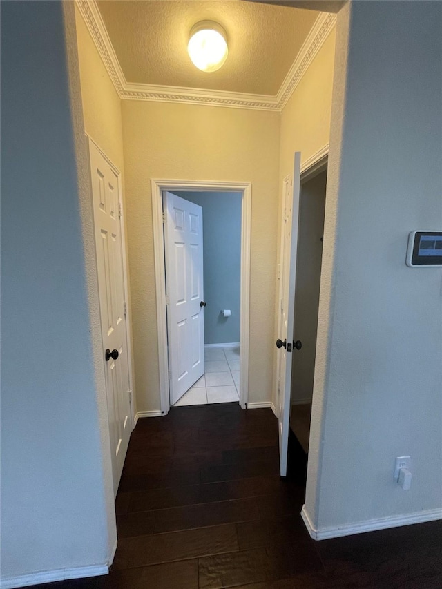 corridor featuring crown molding, a textured ceiling, baseboards, and wood finished floors