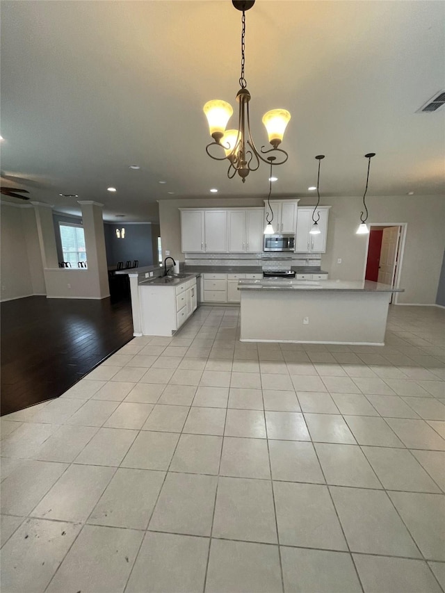 kitchen featuring pendant lighting, visible vents, appliances with stainless steel finishes, open floor plan, and white cabinetry