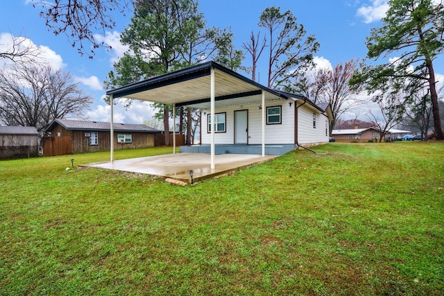 back of house featuring driveway, a lawn, and a patio