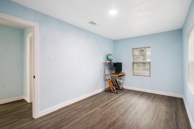 unfurnished room featuring dark wood-style floors, visible vents, and baseboards