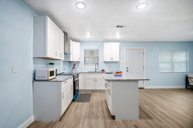 kitchen with stainless steel range with electric stovetop, a center island, white cabinetry, and white microwave