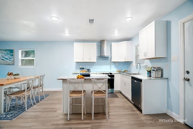 kitchen with wall chimney exhaust hood, a kitchen island, light countertops, and dishwasher