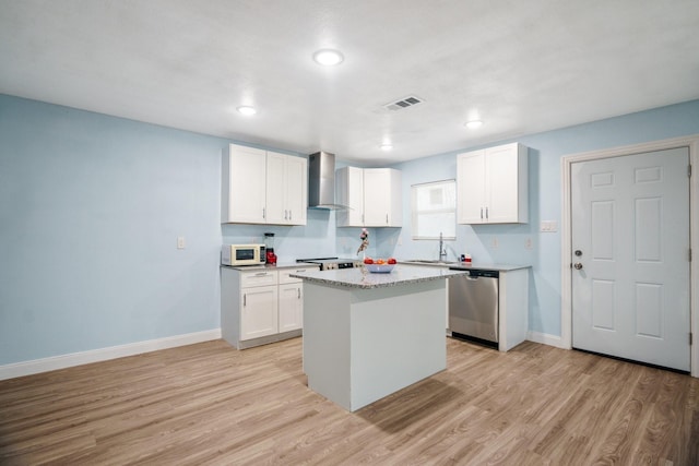 kitchen with stainless steel appliances, wall chimney exhaust hood, white cabinetry, and a center island