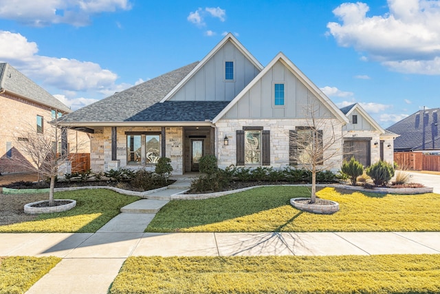 view of front of property featuring roof with shingles, covered porch, board and batten siding, fence, and a front lawn