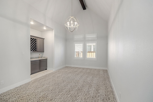 unfurnished room with high vaulted ceiling, light carpet, baseboards, indoor wet bar, and an inviting chandelier